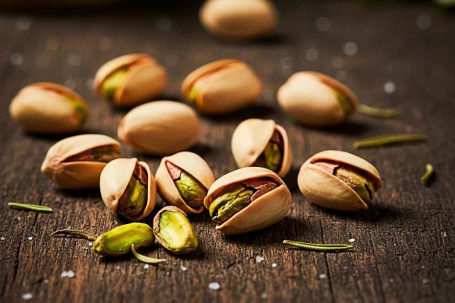 Close-up of roasted pistachios in shells on a dark background.