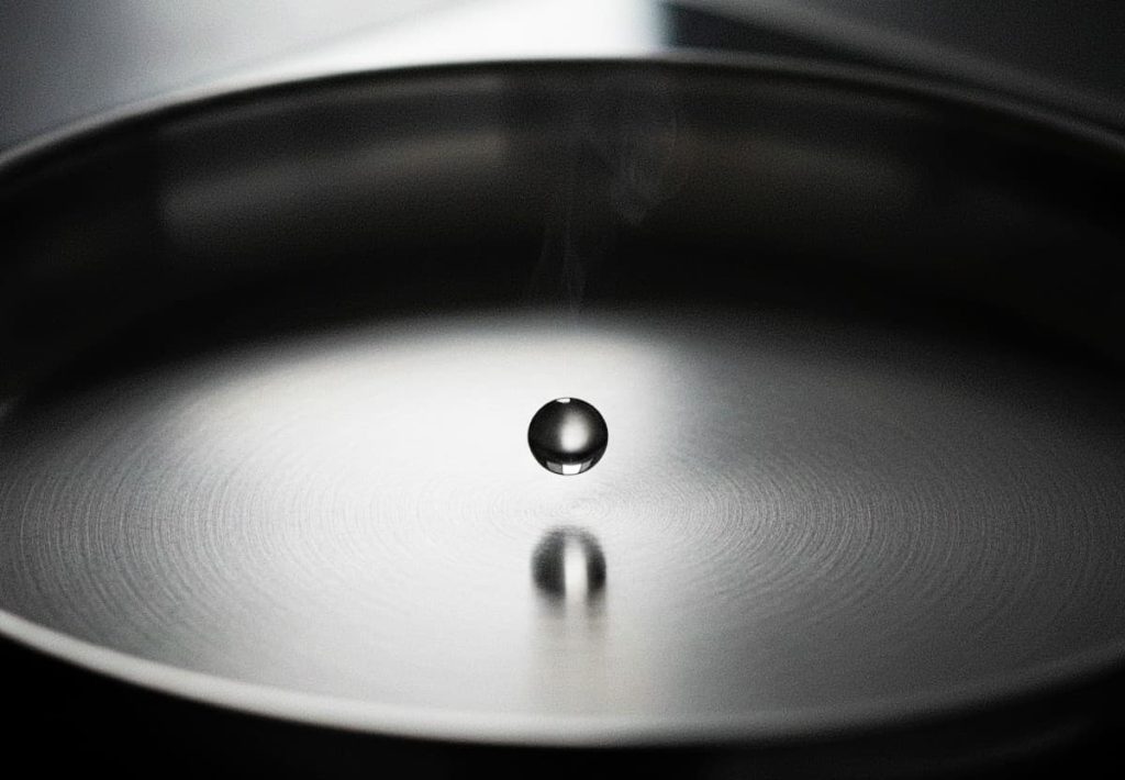 A single water bead dancing on a hot stainless steel surface without evaporating.