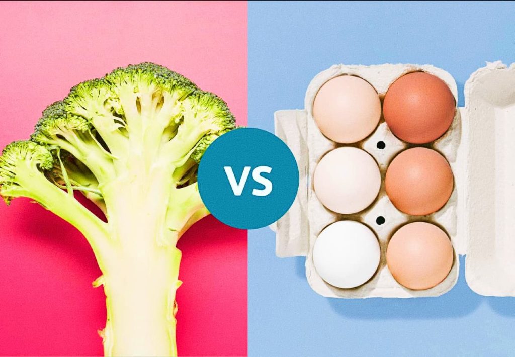 A split-screen graphic with a bright pink background showing a stalk of broccoli on the left and a blue background with a carton of eggs on the right, separated by a "VS" circle.