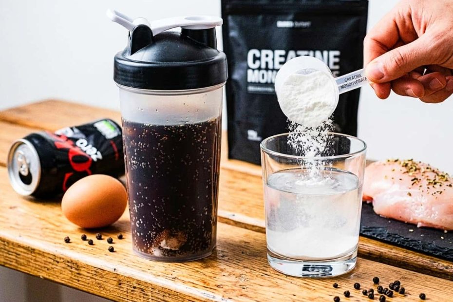 A top-down shot of a rustic wooden bench showing a gym shaker filled with dark, carbonated Coke Zero and sediment, next to a clear glass where white creatine monohydrate powder is being poured into clean water. A whole chicken breast and an egg reference previous articles.