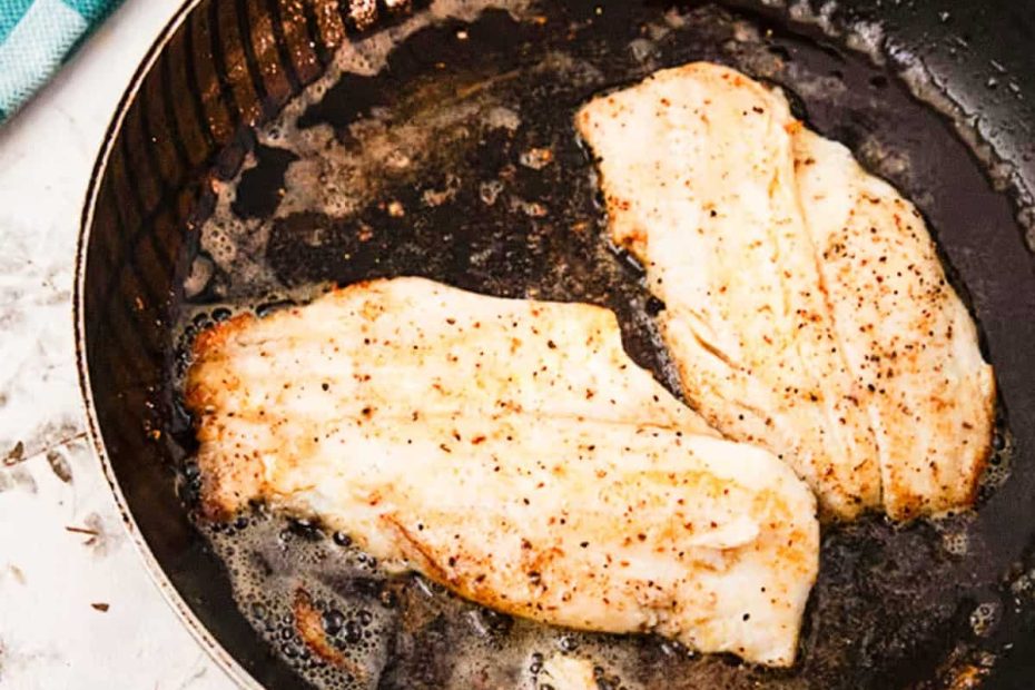 Two seasoned white fish fillets searing in a black frying pan with bubbling oil, showcasing high-protein density.