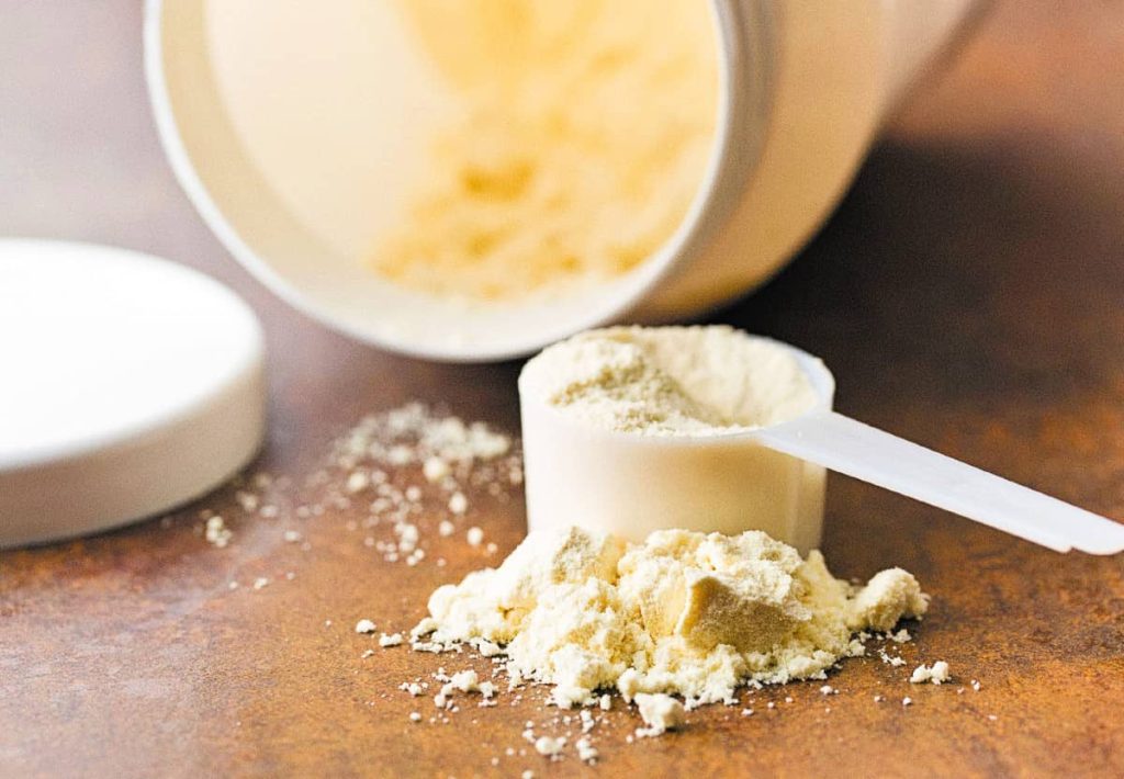 A close-up of a person's hand carefully pouring clear oil into a blue frying pan, representing precision in nutritional measurements.