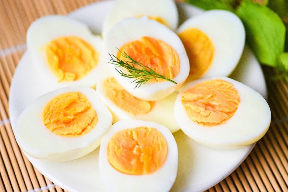 A white plate filled with several hard-boiled egg halves, showing bright orange yolks, garnished with a sprig of fresh dill.