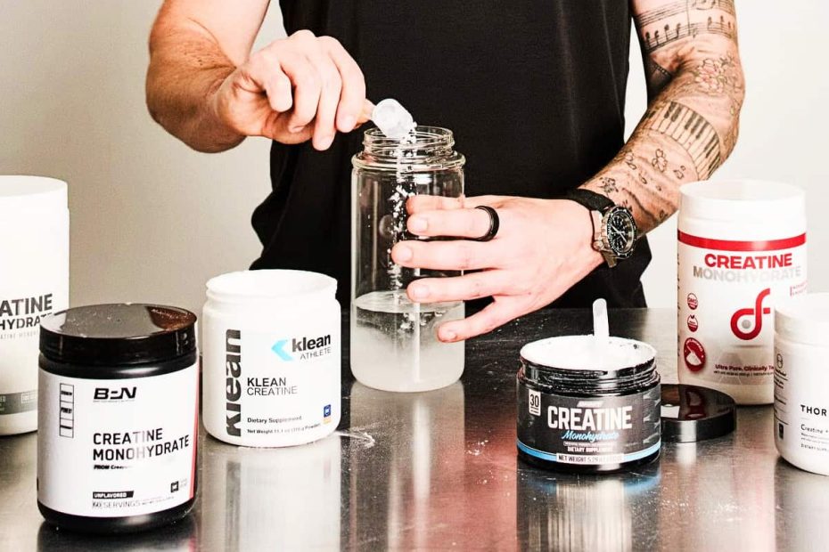 A collection of various creatine supplement brands on a counter with an athlete preparing a dose in the background.
