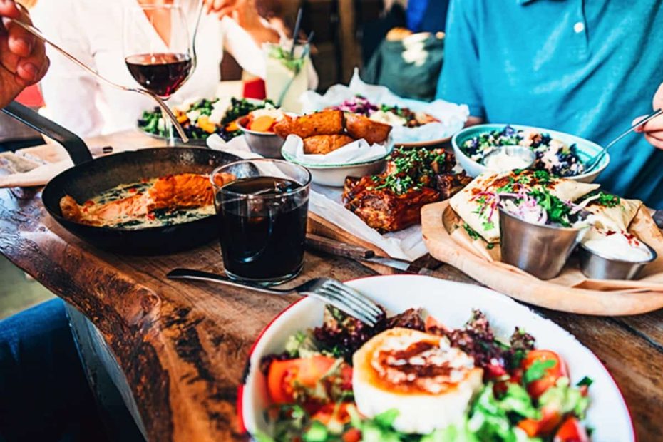 A table filled with various dishes including salmon, salads, and meats, representing a high-protein social meal.