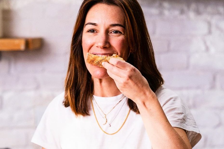 A woman smiling while taking a bite of a slice of bread, representing the balanced approach to carbohydrates in a diabetes diet.