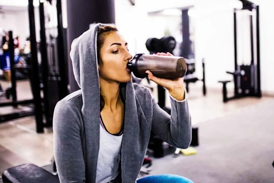 Clear shaker bottle filled with whey protein shake next to a dumbbell representing optimal daily protein timing.