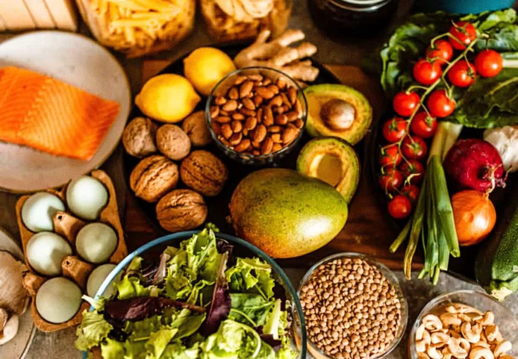 A colorful selection of high-protein foods representing the essential functions of protein in the human body, including salmon, eggs, nuts, and broccoli.