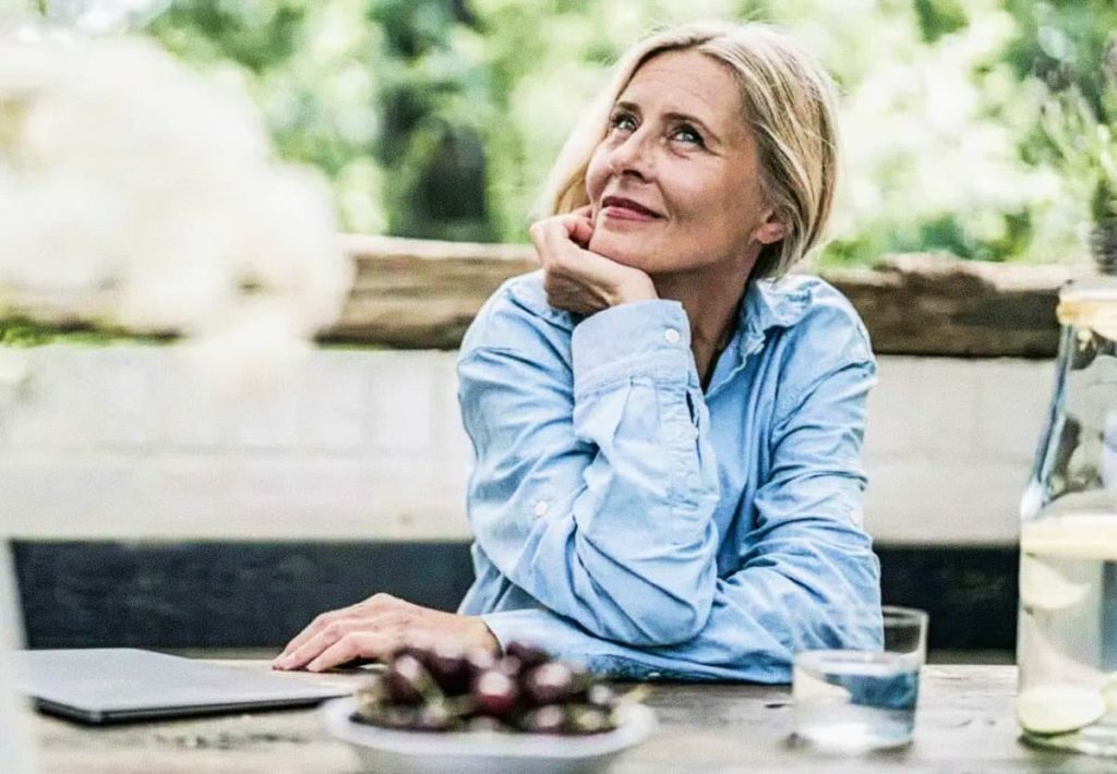 Mature woman reflecting outdoors, representing cellular health and the functions of protein in the body across life stages.