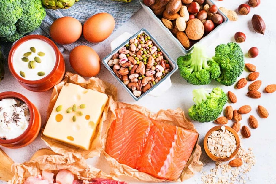 A colorful selection of high-protein foods representing the essential functions of protein in the human body, including salmon, eggs, nuts, and broccoli.
